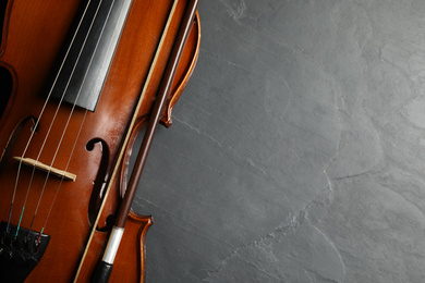 Photo of Classic violin and bow on grey stone background, closeup. Space for text