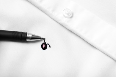 Photo of Pen and stain of black ink on white shirt, top view. Space for text