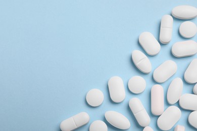 Photo of Many pills on light blue background, flat lay. Space for text