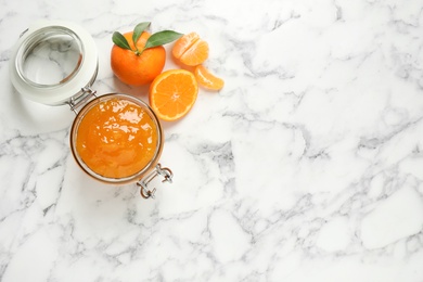 Photo of Flat lay composition with tasty tangerine jam on white marble table. Space for text