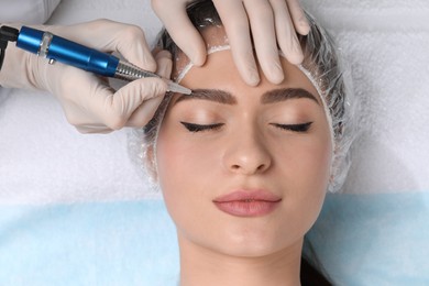 Young woman during procedure of permanent eyebrow makeup in beauty salon, closeup