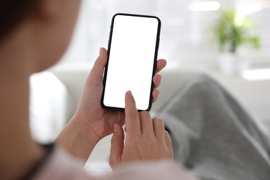 Image of Woman holding mobile phone with empty screen indoors, closeup