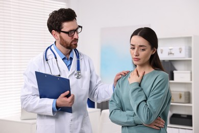 Photo of Doctor with clipboard consulting patient during appointment in clinic