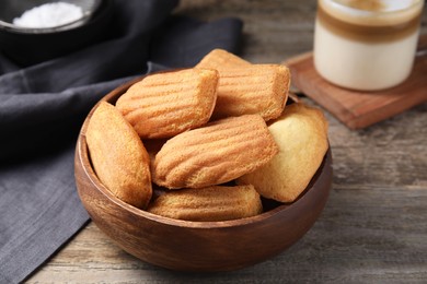 Photo of Tasty madeleine cookies in bowl on wooden table