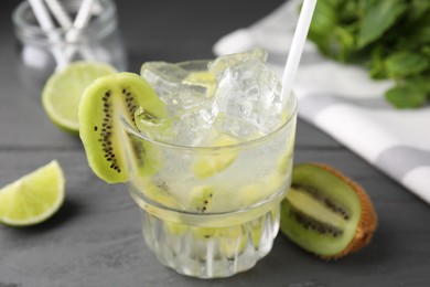 Photo of Glass of refreshing drink and cut kiwi on gray table, closeup