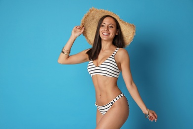 Photo of Pretty sexy woman with slim body in stylish striped bikini on blue background. Space for text