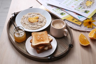 Photo of Wooden tray with delicious breakfast and beautiful flower on table