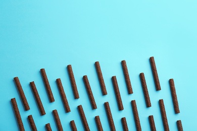 Photo of Flat lay composition with tasty chocolate wafer rolls on color background. Space for text