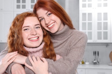 Photo of Portrait of beautiful young redhead sisters in kitchen