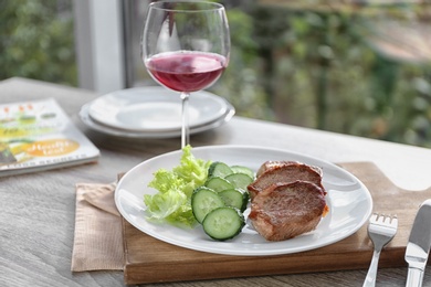 Photo of Plate with delicious meat and vegetables served on wooden table