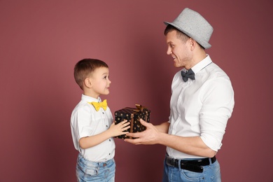 Photo of Man receiving gift for Father's Day from his son on color background