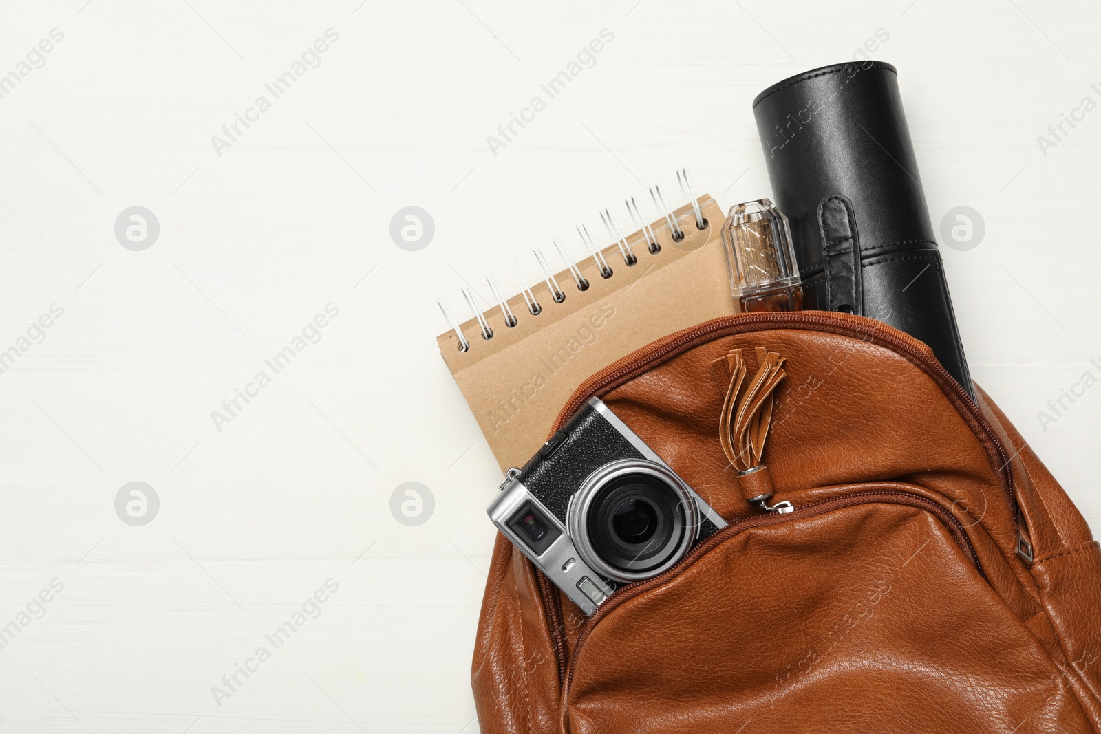 Photo of Stylish urban backpack with different items on white wooden background, top view. Space for text