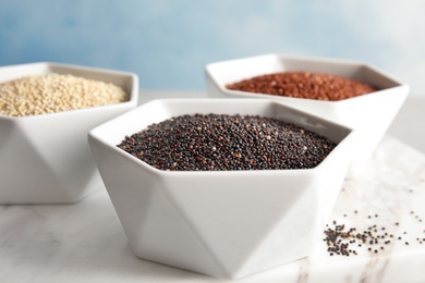 Photo of Bowls with different types of quinoa on stone board