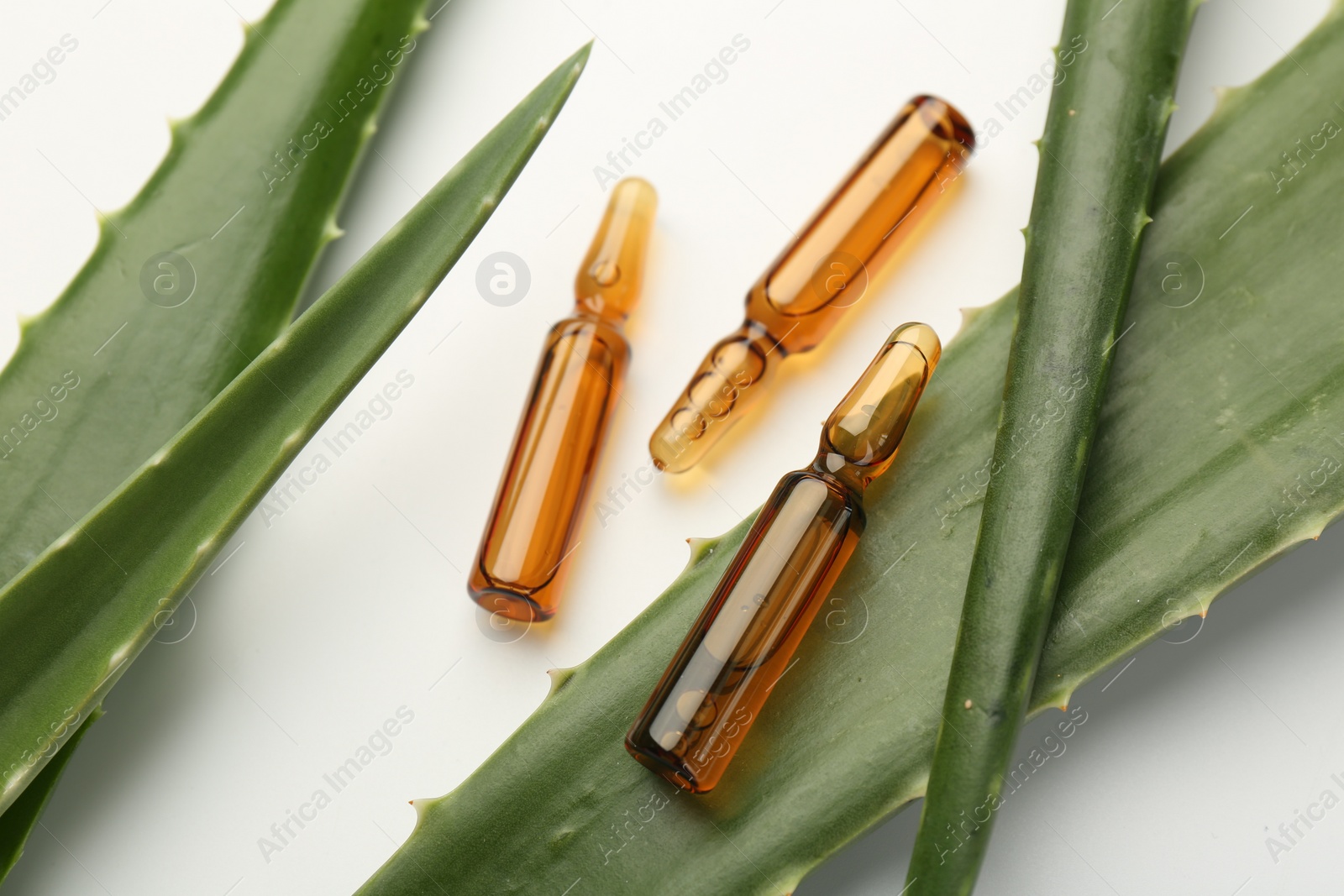 Photo of Skincare ampoules and aloe leaves on white background, closeup