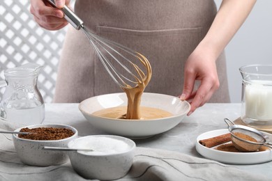 Photo of Woman whipping cream for dalgona coffee at light gray table, closeup