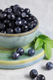 Photo of Tasty fresh bilberries in bowl on white table, closeup