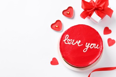 Photo of Bento cake with text Love You, candles, gift box, paper hearts and space for text on white table, flat lay. St. Valentine's day surprise