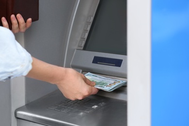 Photo of Woman taking money from cash machine outdoors, closeup