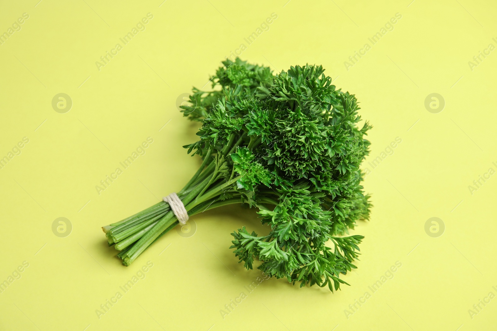 Photo of Bunch of fresh green parsley on yellow background