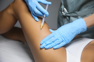 Photo of Young woman getting legs injection in salon, closeup