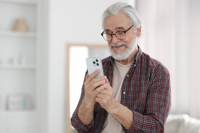 Photo of Portrait of happy grandpa with glasses using smartphone indoors