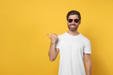 Photo of Portrait of smiling bearded man with stylish sunglasses on orange background. Space for text