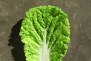 Photo of Fresh Chinese cabbage leaf on gray textured table, top view