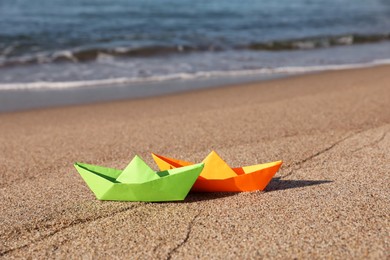 Photo of Bright color paper boats on sandy beach near sea