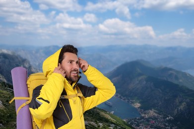 Image of Happy tourist with yellow backpack in mountains