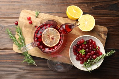 Tasty hot cranberry tea, lemon, rosemary and fresh berries on wooden table