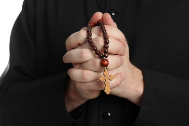 Photo of Priest with rosary beads praying on white background, closeup