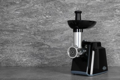 Photo of Modern electric meat grinder on grey table. Space for text