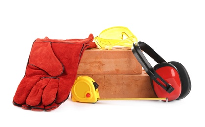 Photo of Composition with safety equipment, measuring tape and bricks on white background. Construction industry