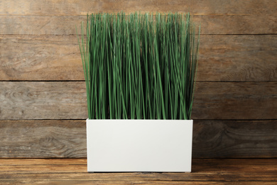 Photo of Artificial plant in white flower pot on wooden table