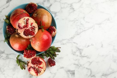 Photo of Delicious ripe pomegranates on white marble table, flat lay. Space for text