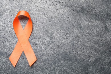 Photo of Orange ribbon on grey table, top view with space for text. Multiple sclerosis awareness