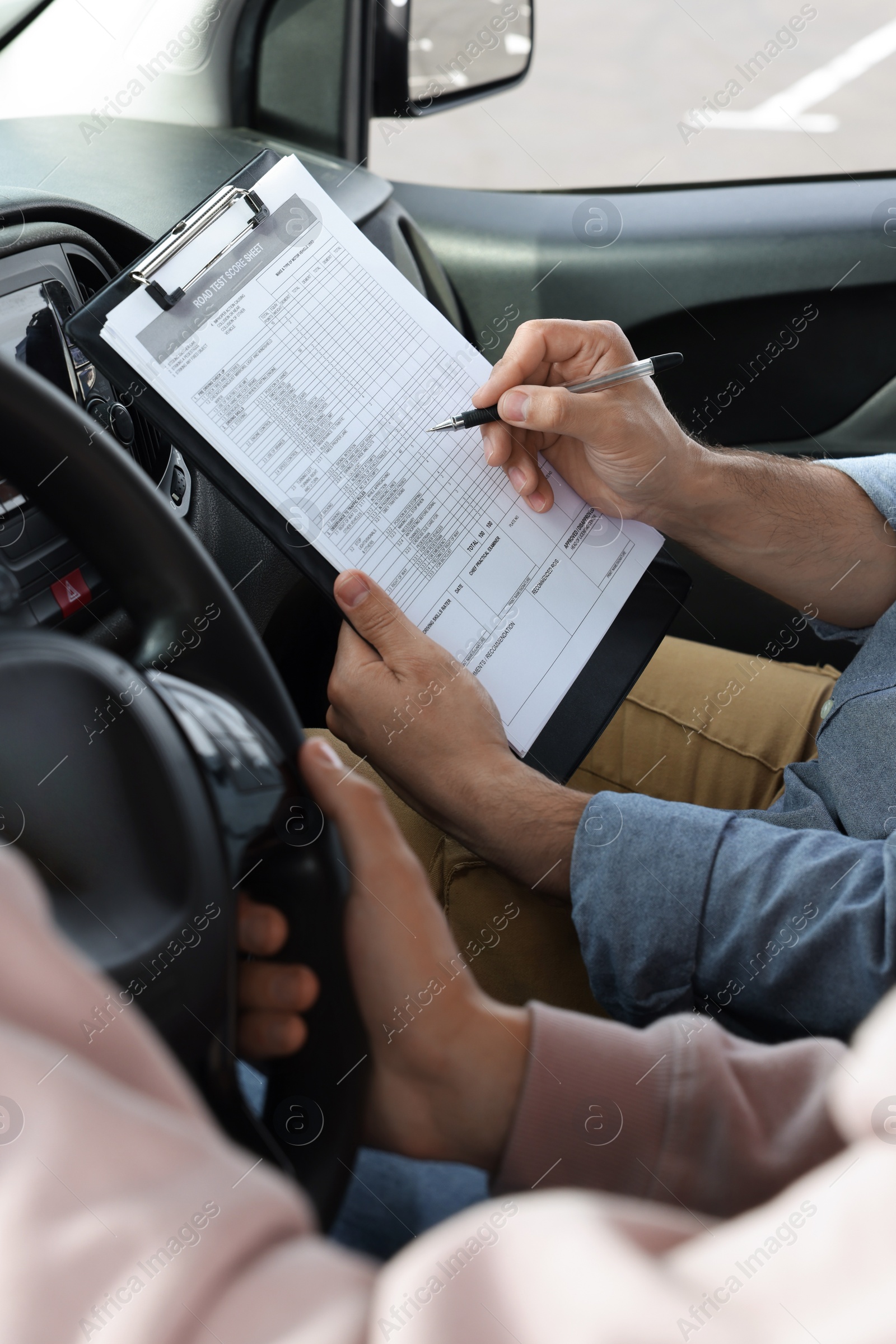 Photo of Driving school. Student passing driving test with examiner in car, closeup