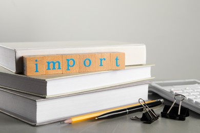Photo of Word Import made of wooden cubes and office stationery on grey table, closeup