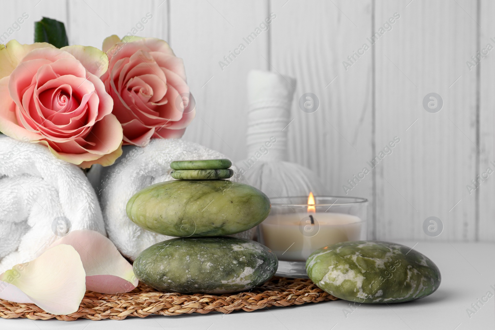 Photo of Composition with different spa products, roses and candle on white table against wooden background. Space for text