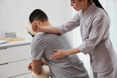 Photo of Man receiving massage in modern chair indoors