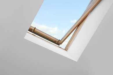 Photo of Skylight roof window and lamps on slanted ceiling in attic room, low angle view