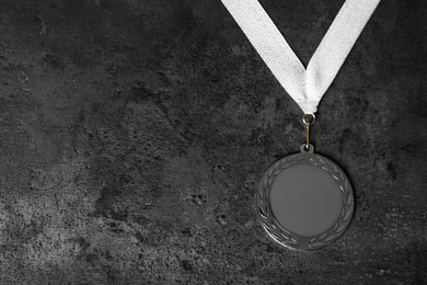 Photo of Silver medal on grey stone background, top view. Space for design