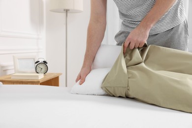 Photo of Man changing pillowcase at home, closeup. Domestic chores
