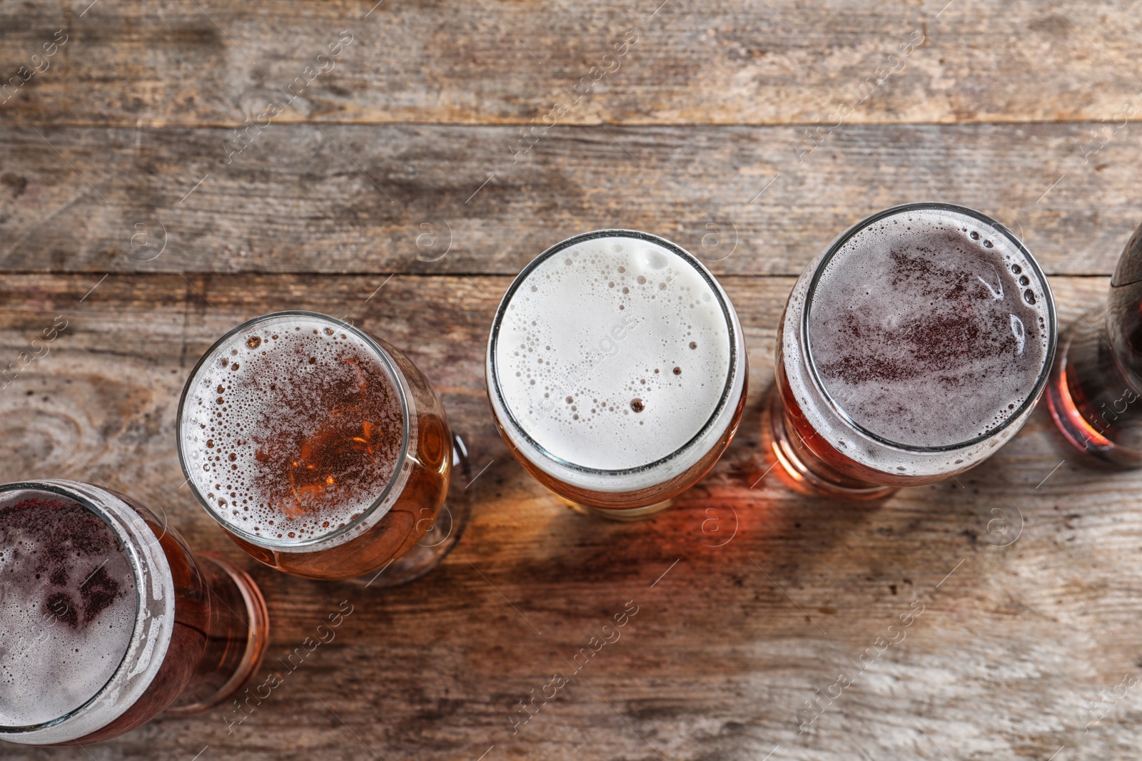 Photo of Glasses with different types of cold tasty beer on wooden background