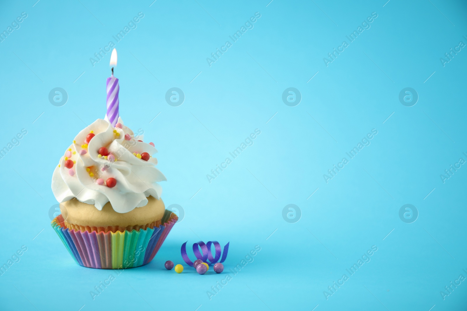 Photo of Delicious birthday cupcake with candle on light blue background. Space for text