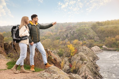 Couple of travelers with backpacks enjoying beautiful view near mountain river. Autumn vacation