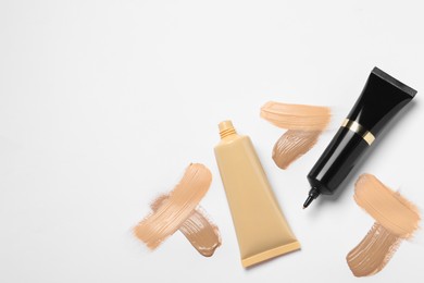 Photo of Liquid foundations and swatches on white background, flat lay. Space for text