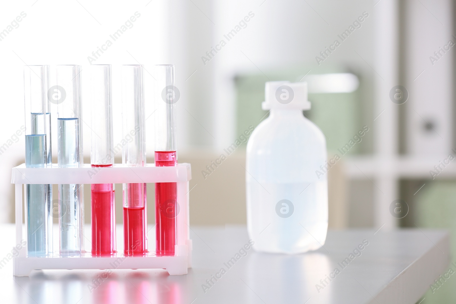 Photo of Rack with test tubes and bottle on table in laboratory. Research and analysis