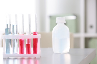 Photo of Rack with test tubes and bottle on table in laboratory. Research and analysis