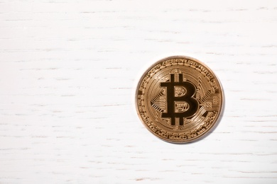 Photo of Golden bitcoin on wooden table, top view. Space for text